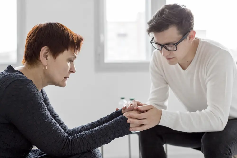 Terapeuta y familiar tomados de las manos durante una sesión de orientación familiar en Centro Vida Nueva